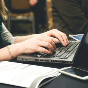 Bilden visar en person som sitter vid en laptop